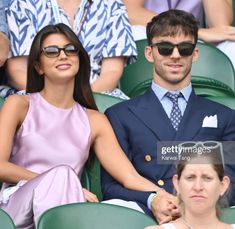 a man and woman sitting next to each other at a tennis match in the stands