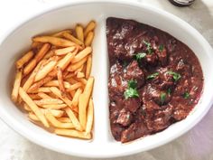 a white bowl filled with meat and fries