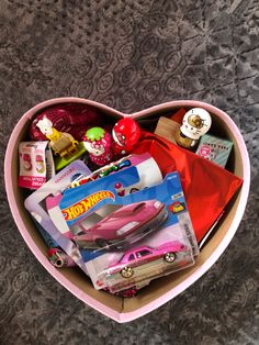 a heart shaped box filled with toys and other items on top of a carpeted floor