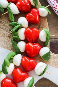 several red and white peppers are arranged on skewers with green leafy leaves