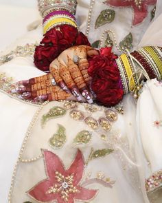 the hands of a bride are adorned with red flowers