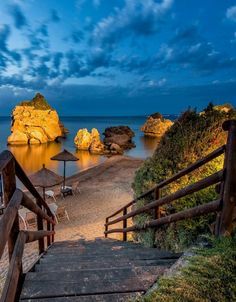 steps lead down to the beach with umbrellas and chairs on it at night time