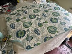 an unmade bedspread with blue and green designs sitting on top of it