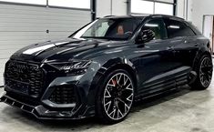 the front end of a black audi suv parked in a garage with its door open