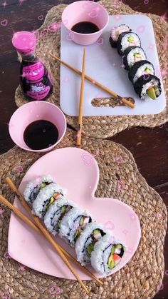 sushi on a plate with chopsticks and sauce in a heart shaped bowl