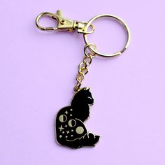 a keychain with a black cat on it's back and stars around the neck