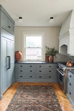 a kitchen with blue cabinets and an area rug in front of the stove top oven