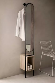 a white chair sitting next to a wooden shelf with a mirror on top of it