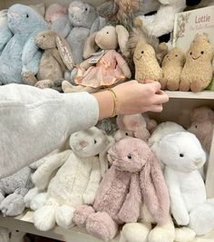 a person is picking up stuffed animals from a shelf in a toy store or nursery