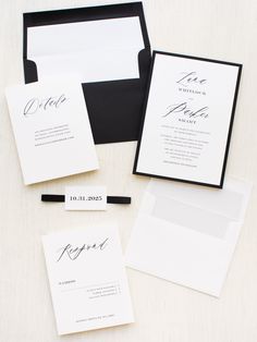 the wedding stationery is set up with black and white cards, envelopes, and calligraphy