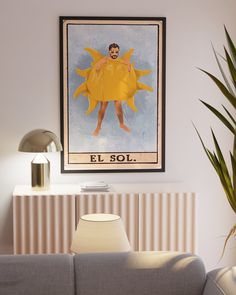 a poster hangs on the wall above a couch in a living room with a lamp