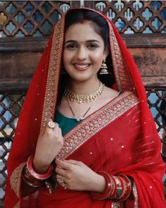 a woman in a red sari smiles for the camera