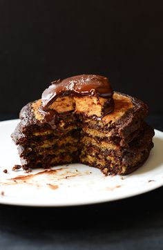 a stack of chocolate pancakes on a plate with one slice cut out and the other half eaten