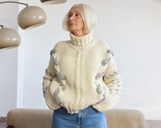 an older woman standing in front of a couch with lamps on the wall behind her