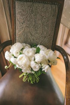 a bouquet of white flowers sitting on top of a wooden chair