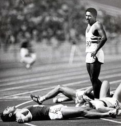 a man standing on top of a race track next to another man laying on the ground