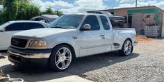 a white pick up truck parked in front of a building with other trucks behind it