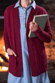 a woman is holding a book in her hand and wearing a red cardigan sweater