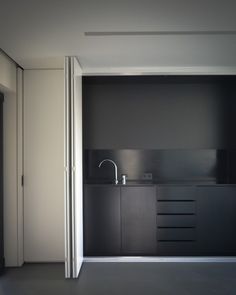 an empty room with a sink and cabinets in the corner on the right side of the room