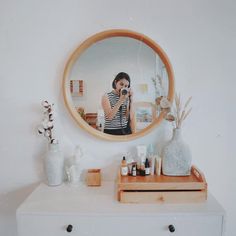 a woman taking a selfie in front of a mirror on top of a dresser