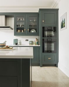 a kitchen with dark green cabinets and white counter tops is seen in this image from the front view