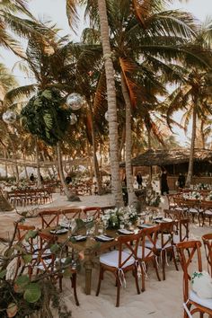 tables and chairs are set up on the beach for an outdoor wedding reception with palm trees in the background