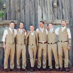 a group of men standing next to each other in front of a wooden building with windows