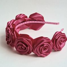 a close up of a pink rose headband on a white surface with one flower in the middle