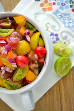 a white bowl filled with lots of different colored veggies next to a spoon