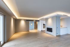 an empty living room with white walls and wood flooring is lit by recessed lighting