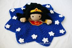 a crocheted doll laying on top of a blue blanket with white stars around it