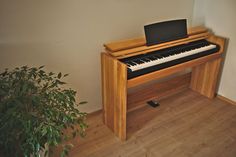 a piano sitting on top of a wooden floor next to a potted plant