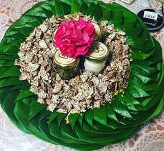 two jars with flowers in them sitting on a green leafy plate next to other items