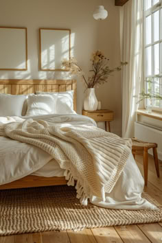 a bed with white sheets and blankets on top of it in a bedroom next to a window