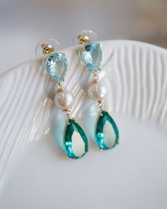 Adorned with vivid emerald and sky-blue cubic stones and featuring a freshwater pearl drop, these exquisite Elina Blue Cubic Pearl Earrings will make a sophisticated statement on any occasion - be it for day-to-day exploring, special events, or gifting a special someone. As part of the Artisan Made collection, this particular piece is one-of-a-kind - making it even more special and desirable. Follow me on Instagram: @cubic_jewels Turquoise Pearl Drop Earrings, Elegant Turquoise Pearl Drop Earrings, Elegant May Birthstone Blue Jewelry, Blue Gemstone Pearl Drop Earrings, Blue Teardrop Pearl Earrings With Gemstone, Wedding Jewelry Earrings, Cluster Earrings, Pearl Drop, Art Clothes