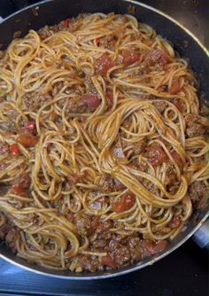 a pan filled with spaghetti and meat on top of a stove burner next to a spatula