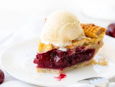 a piece of pie with ice cream on top and cherries in the back ground