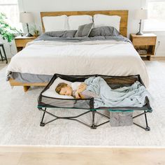 a baby is sleeping in a bed with an iron frame and clear glass coffee table