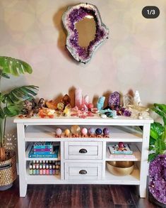 a white table topped with lots of different types of rocks and plants next to a mirror