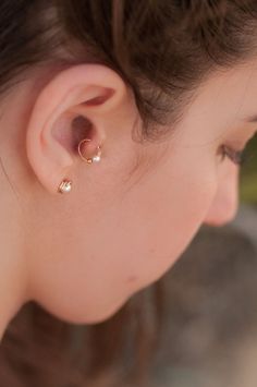 a close up of a woman's ear with two small gold earrings on it