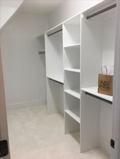 an empty white closet with shelves and a shopping bag on the shelf next to it