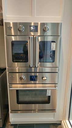 a stainless steel oven in a kitchen with tile flooring and white cabinets on either side