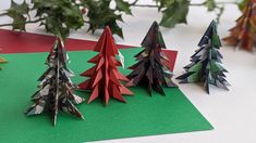 three origami christmas trees sitting on top of green paper