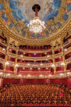 an empty auditorium with chandelier and painted ceiling