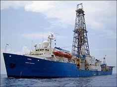 a large blue and white boat in the water with a crane on it's side