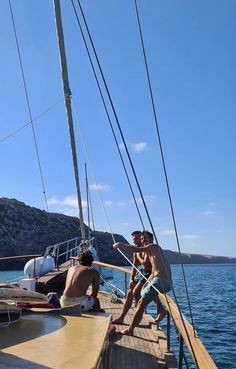 two men sitting on the deck of a sailboat