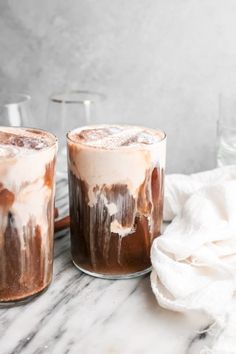 two glasses filled with ice cream sitting on top of a marble counter next to each other