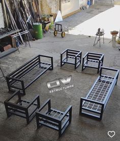 several black metal benches sitting in the middle of a yard with construction equipment behind them