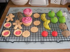 there are many different cookies and cupcakes on the cooling rack with icing