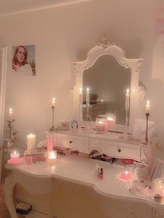 a dressing table with candles and pictures on the wall